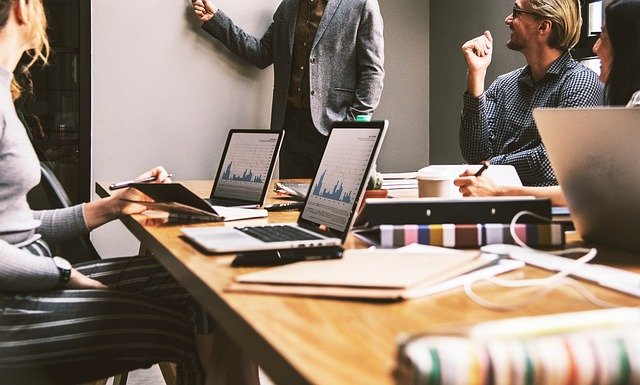 Reunião do conselho fiscal. Sobre a mesa, laptops mostrando gráficos. Ao redor da mesa, os conselheiros prestando atenção na apresentação que está sendo feita.